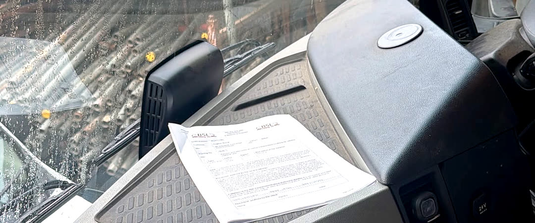 A BSL risk assessment and method statement on the dashboard of a site vehicle, with the scaffold visible through the windscreen