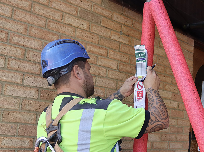 A BSL scaffolder signing the scaff tag on a completed structure